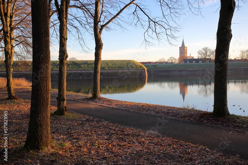 Obraz na płótnie The fortifications and moats of the city of Naarden, Netherlands, with the Grote Kerk church in the background. Picture taken after sunrise in winter in the woods surrounding Naarden w salonie