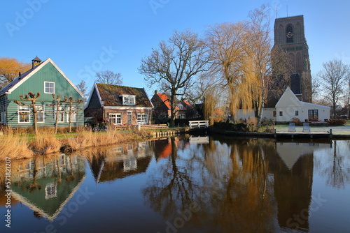 Reflections of traditional wooden houses and the Kerk van Ransdorp (church of Ransdorp) on a canal in the village of Ransdorp, North Holland, Netherlands, located near Amsterdam