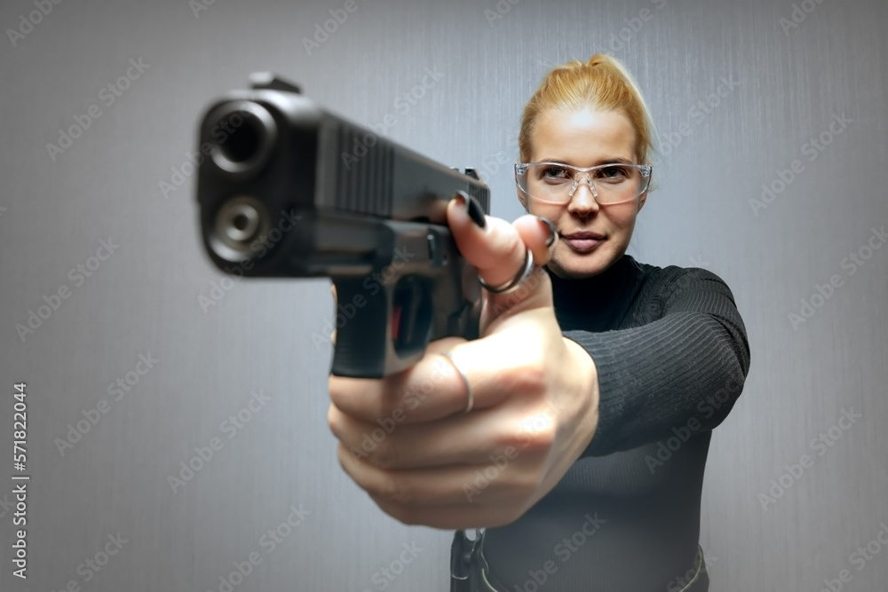 A girl in goggles is aiming a gun, low contrast photo as an artistic technique. A girl in goggles is aiming a gun, low contrast photo as an artistic technique.
