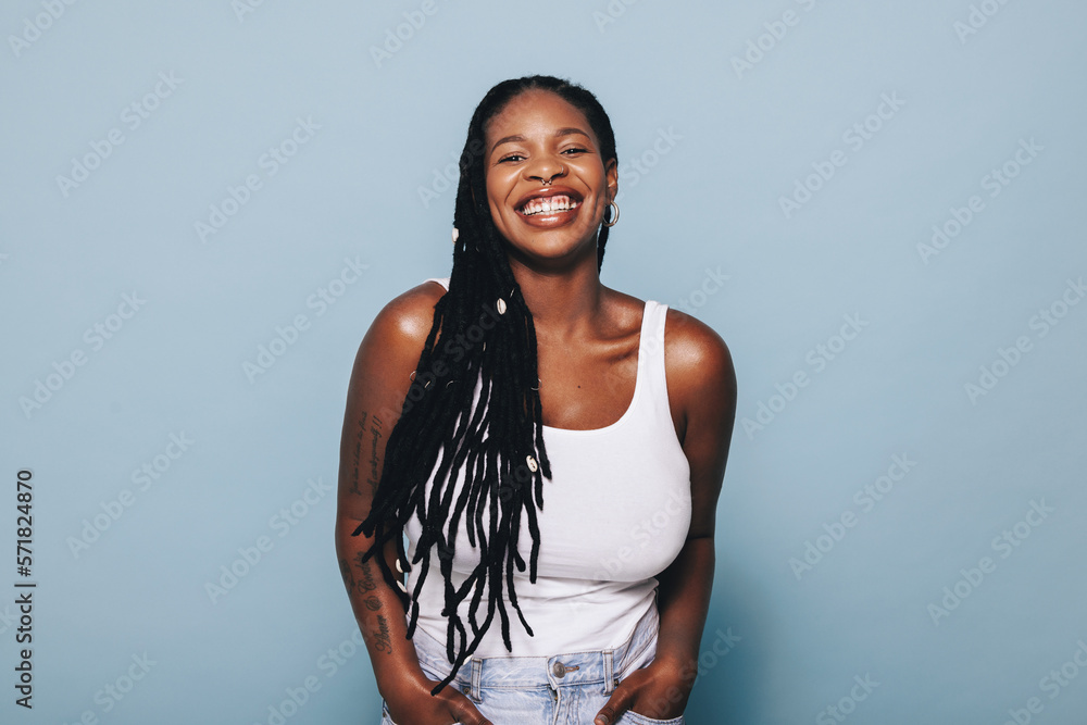 © Jacob Lund - Happy young black woman smiling at the camera while standing in a studio in casual clothing © Jacob Lund - Happy young black woman smiling at the camera while standing in a studio in casual clothing