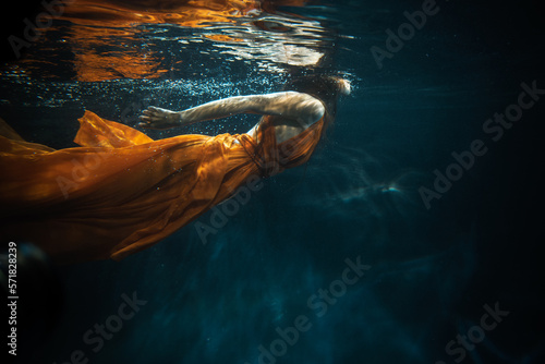 Young beautifull caucasian woman in orange dress under water