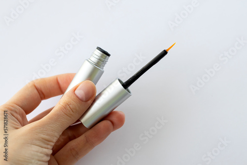 Eyebrow Serum for Women. Thin brush serum in a girl's hand with essential oils and peptides on her eyebrows for strong growth, density and problem solving. Close-up.