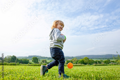 a little boy playing balls and having fun on a green field in the country side, Caurel Brittany, France. photo