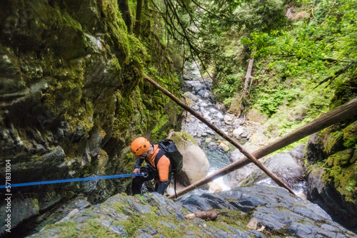 Man rappelling beside waterfall in Frost Creek Canyon.