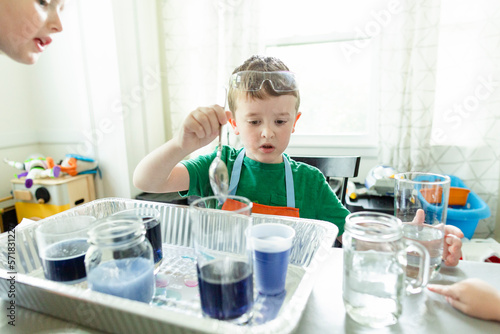 Elementary age boy focused doing chemistry science experiment at home photo
