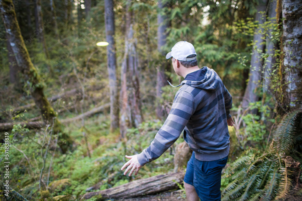 Man throws frisbee in forest during a disk golf game. Man throws frisbee in forest during a disk golf game.