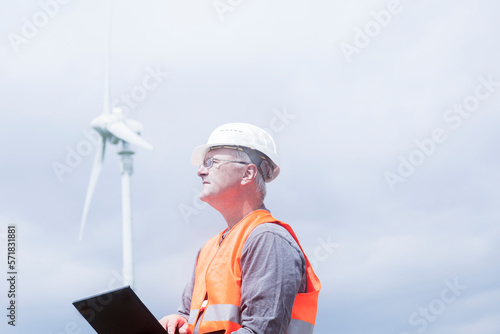 older energy engineer in front of a windmill photo