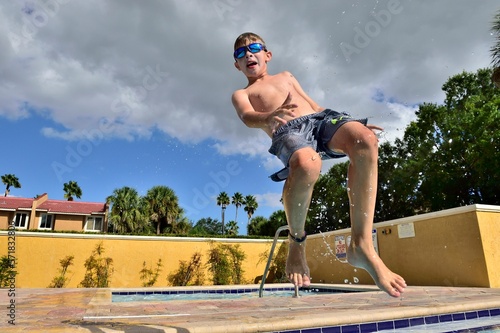 Boy has fun jumping into a hotel pool on vacation