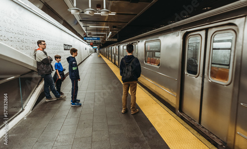 Father and three sons waiting to ride the subway in New York City.