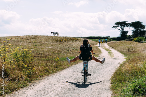 Pretty young woman riding bicycle with open legs in a country road