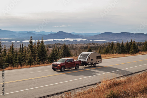 Pickup truck and RV camper drive along scenic road in Jackman, Maine