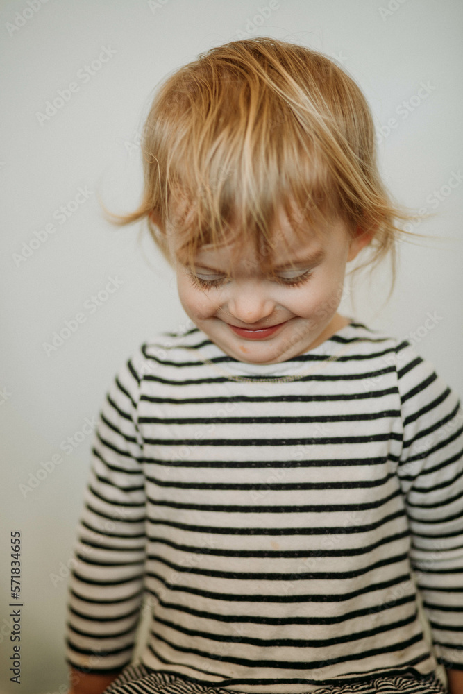 portrait of toddler smiling at ground with white background portrait of toddler smiling at ground with white background