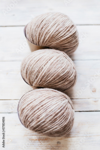 Three coils of wool light threads for knitting. Yarn for knitting things on a wooden background.