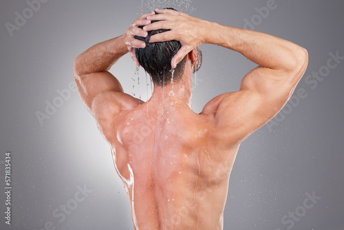Shower, cleaning and back of man with water in studio background for wellness, grooming and beauty. Skincare, bathroom hygiene and male smile for washing hair, clean body and soap for healthy skin