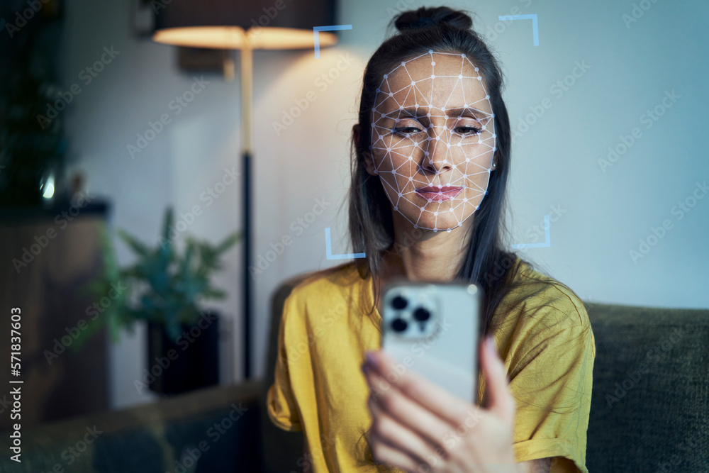 Young woman using phone with face recognition