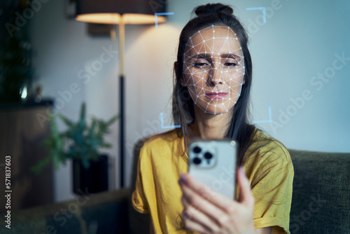 Young woman using phone with face recognition photo