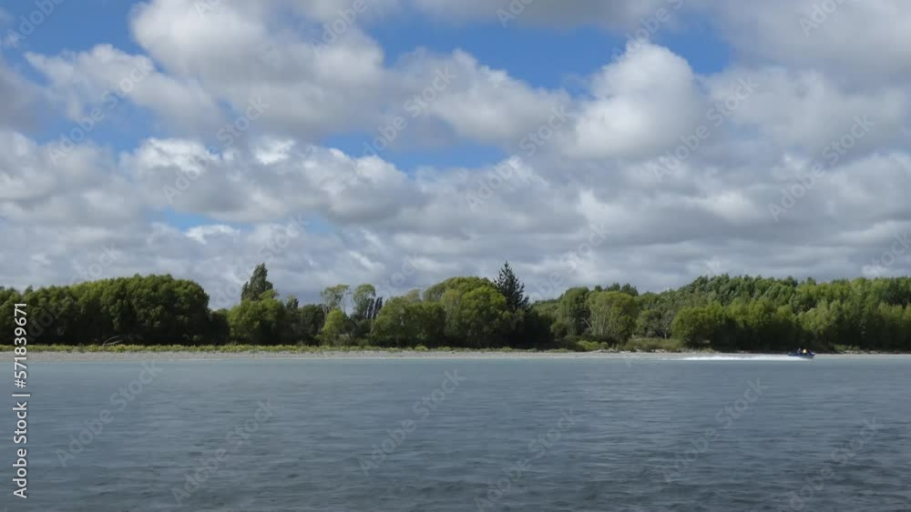 Jetboats head upstream beside deep-green willow trees on a cloudy summer's day - Waimakariri River (New Zealand) Jetboats head upstream beside deep-green willow trees on a cloudy summer's day - Waimakariri River (New Zealand)