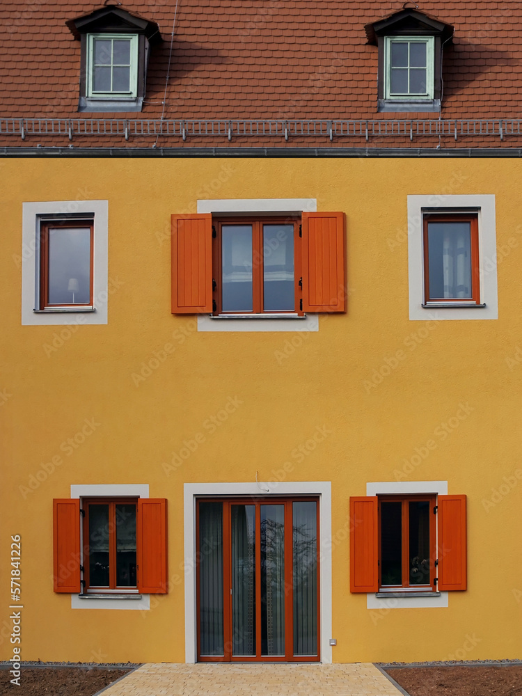 Gelbe Hausfassade mit Eingangstür und Fenstern