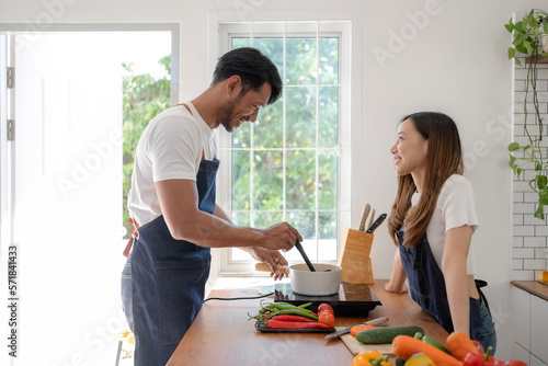 Happy Asian couple preparing food to cook breakfast in the kitchen And have fun cooking.