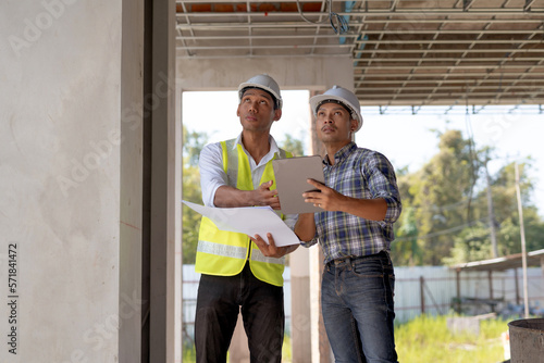 Two young Asian engineer visit the construction site, consult and work on site.