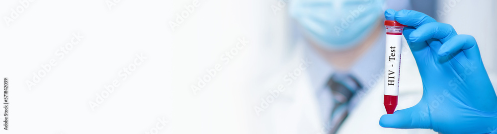 Fototapeta premium Doctor's hand holds test tube in blood.Blood sample positive with HIV testing. Banner. Copy space for text