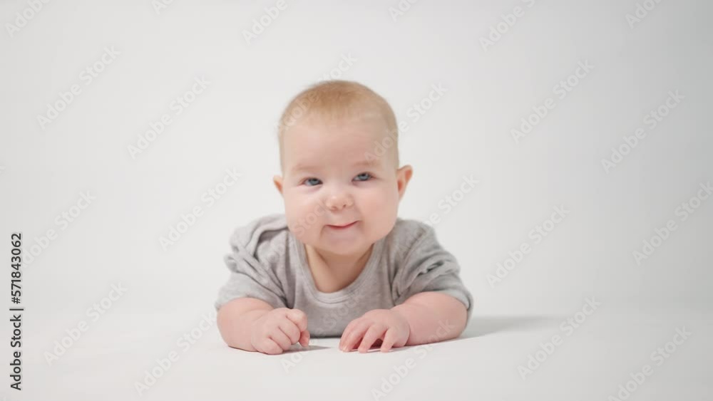 Portrait of a baby. A baby lying on his stomach in close-up against a white background, looking at the cameraman Portrait of a baby. A baby lying on his stomach in close-up against a white background, looking at the cameraman