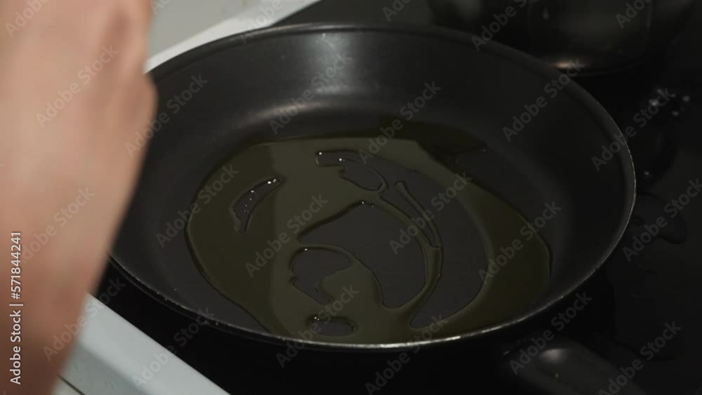 Young brown woman pouring olive oil into a pan on the stove and closing bottle. Young brown woman pouring olive oil into a pan on the stove and closing bottle.
