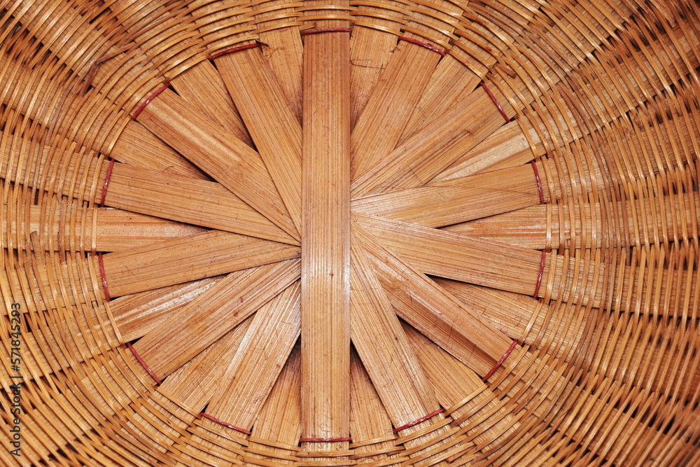 Weaved bamboo background. Closeup of woven bamboo surface painted light red by hand making household utensils in rural Thailand with selective focus.