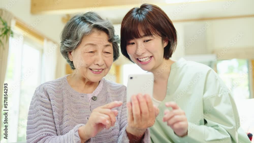 孫にスマートフォンの使い方を教わるシニア女性 孫にスマートフォンの使い方を教わるシニア女性