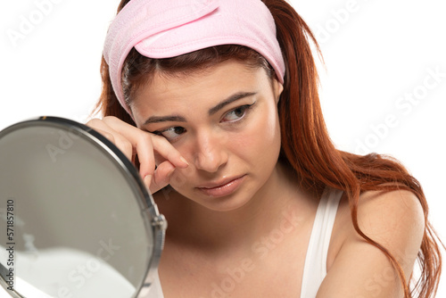 Portrait of dissappointed lonely crying beautiful woman with long straight ginger hair on a white background