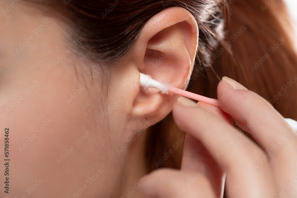 Obraz premium Young woman cleaning ear with cotton swab , closeup