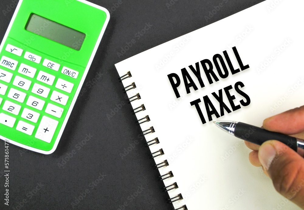 calculator, book and hand holding a pen with the word payroll taxes. business and tax concepts