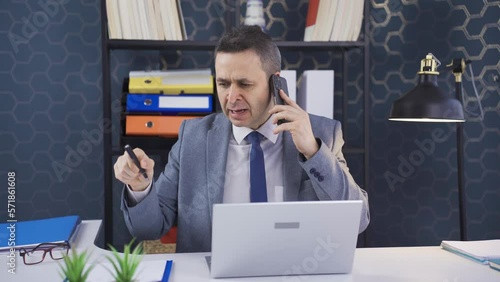 hile talking about work problems on the phone in the office, he gets angry and cannot control his anger.
Office worker man hears on the phone that he is in trouble with something and shouts in anger,  photo