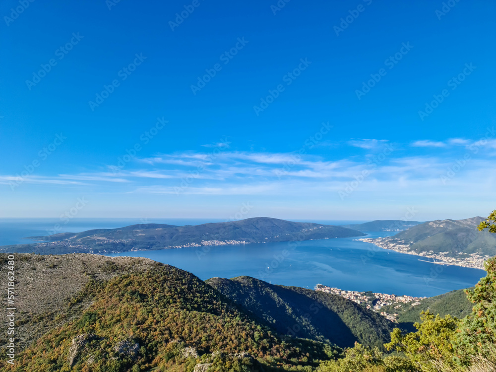Panoramic view from mountain summit of Sveti Ilija on Kotor bay in sunny summer, Adriatic Mediterranean Sea, Montenegro, Balkans, Europe. Fjord winding along coastal town Tivat. Hiking in Dinaric Alps