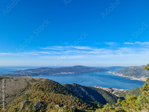 Panoramic view from mountain summit of Sveti Ilija on Kotor bay in sunny summer, Adriatic Mediterranean Sea, Montenegro, Balkans, Europe. Fjord winding along coastal town Tivat. Hiking in Dinaric Alps