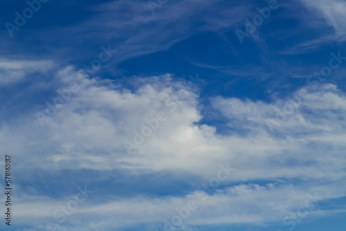 Sunny weather with cumulus and cirrus clouds on blue sky.