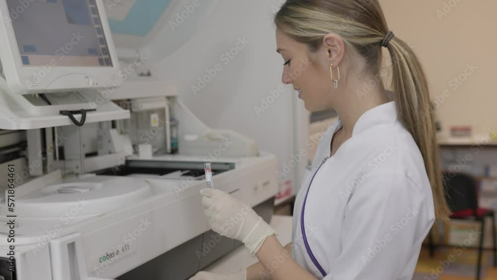 Portrait of a young female laboratory assistant making analysis with test tubes and analyzer machines sitting at the modern laboratory Portrait of a young female laboratory assistant making analysis with test tubes and analyzer machines sitting at the modern laboratory