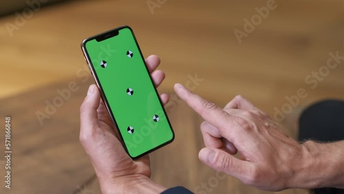 The man uses a black smartphone. Hands in a close-up business suit. Office minimalist interior. Tap and sharp swipe from left to right. Gestures to control the touch screen. Close-up. Green screen.
