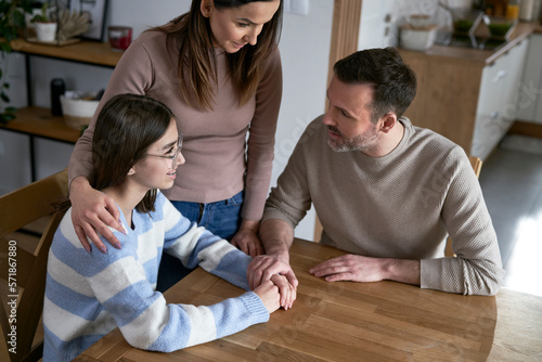 Caucasian parents talking with teenager girl and sitting around the table