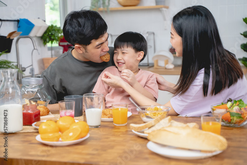 happy family together. Asian parent eating breakfast with little son in the kitchen.