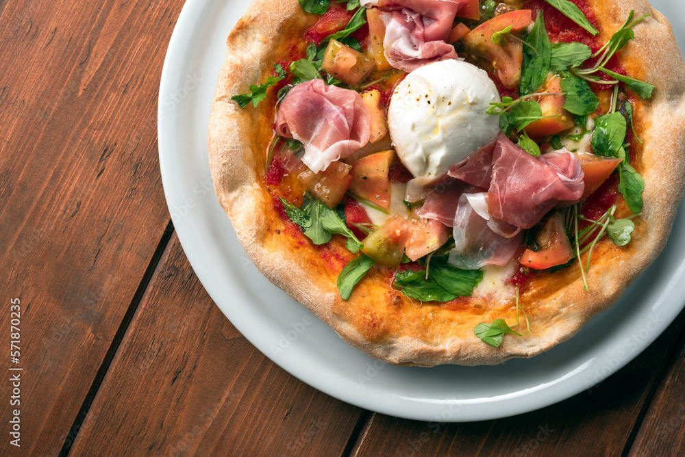 Deliziosa pizza condita con pomodoro fresco, mozzarella di bufala, rucola e prosciutto crudo, cibo italiano Deliziosa pizza condita con pomodoro fresco, mozzarella di bufala, rucola e prosciutto crudo, cibo italiano