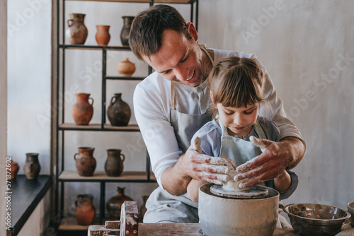 Little girl working with clay on potter's wheel