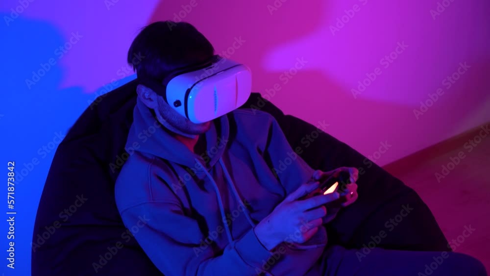 Male cybersport gamer with controller playing game in virtual reality goggles Male cybersport gamer with controller playing game in virtual reality goggles