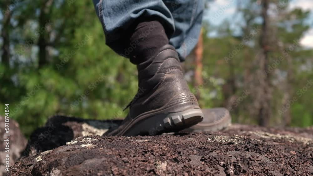 tourist in trekking boots going along rocky road against backdrop of beautiful forest landscape. man walks through mountains to goal. closeup of legs of climber, tourist-traveler. concept of travel. tourist in trekking boots going along rocky road against backdrop of beautiful forest landscape. man walks through mountains to goal. closeup of legs of climber, tourist-traveler. concept of travel.