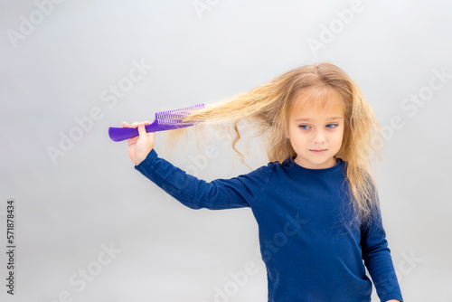 Cute girl with a comb and flowing blond long hair
