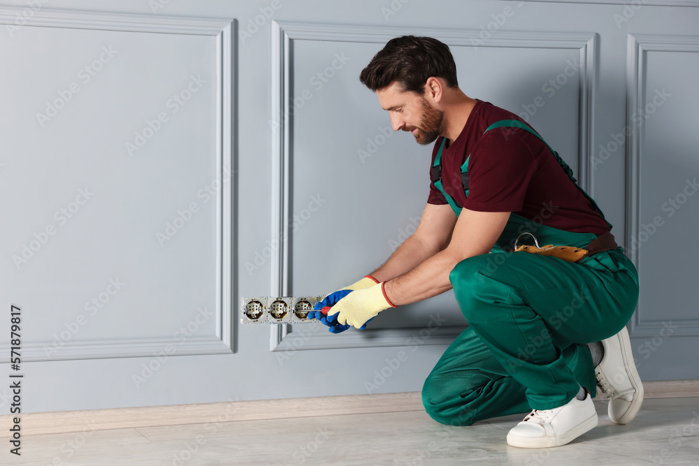 Electrician with screwdriver repairing power sockets indoors Electrician with screwdriver repairing power sockets indoors