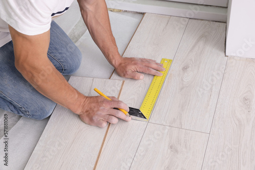 Man using measuring tape during installation of laminate flooring, closeup