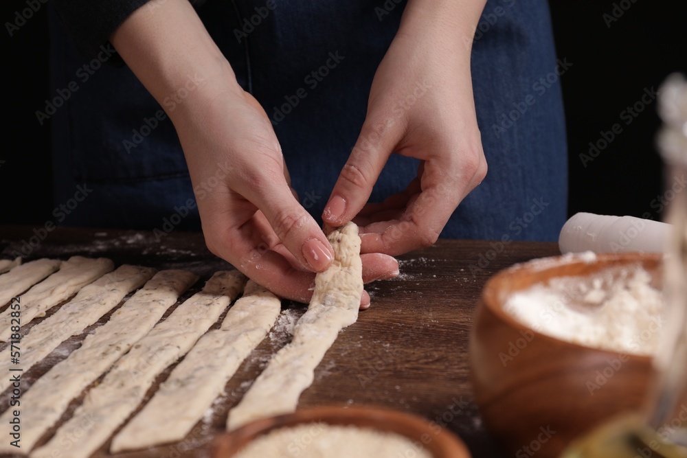 Woman making grissini at wooden table, closeup Woman making grissini at wooden table, closeup