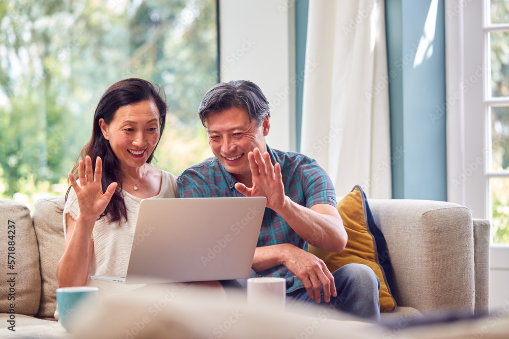Mature Couple Sitting On Sofa At Home Making Video Call On Laptop Mature Couple Sitting On Sofa At Home Making Video Call On Laptop