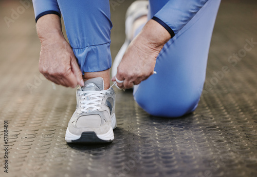 Hands, sports and tie shoes in gym to start workout, training or exercise for wellness. Fitness, athlete health or senior woman tying sneakers or footwear laces to get ready for exercising or running